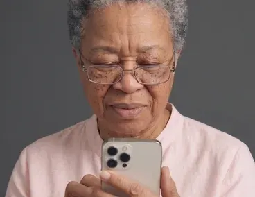 An older woman reading a message on her phone